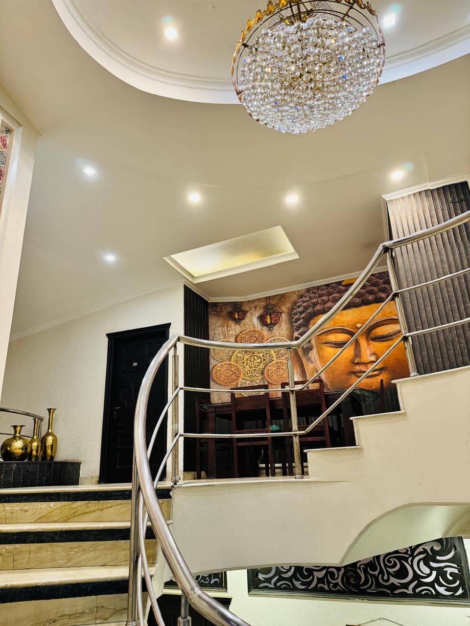 Una gran escalera con un mural, una araña y una lámpara moderna.