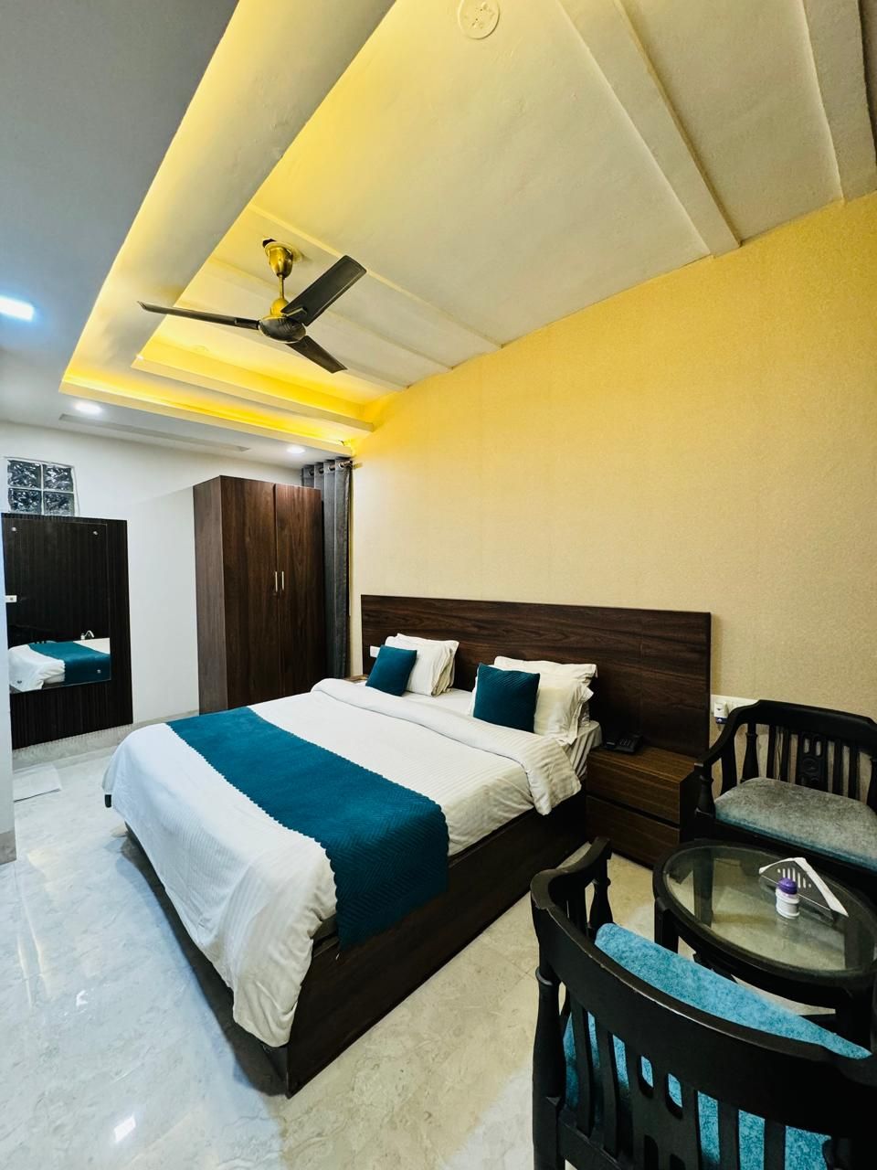A modern bedroom with a large bed, a ceiling fan, and a small round table.