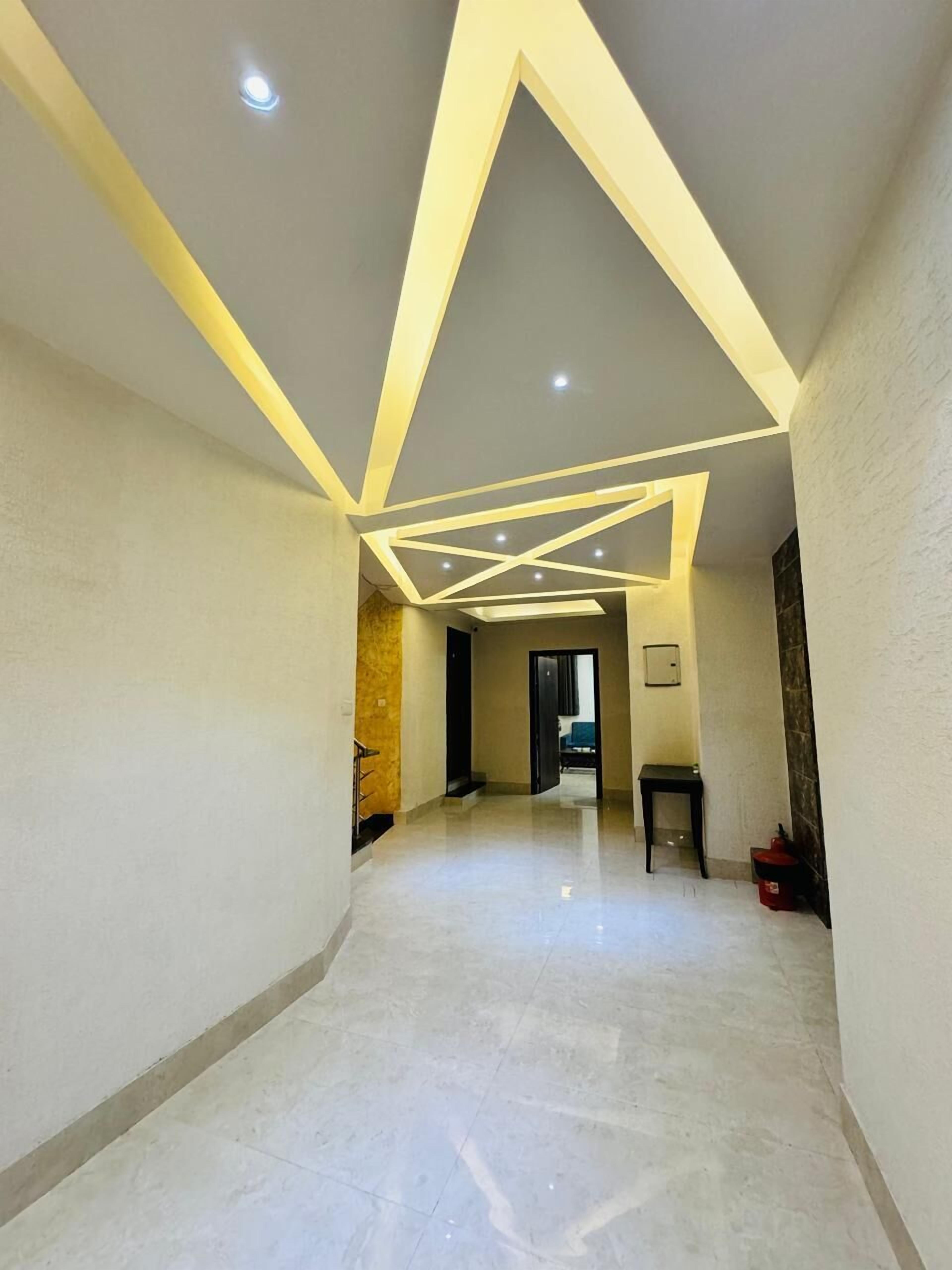 Un corridoio con un moderno design del soffitto, caratterizzato da luci a incasso e motivi geometrici.