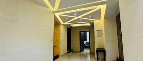 Un corridoio con un moderno design del soffitto, caratterizzato da luci a incasso e motivi geometrici.