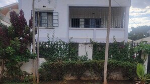 A white two-story building with a large window and barred window. - ALPHA RETREAT (Kisumu)