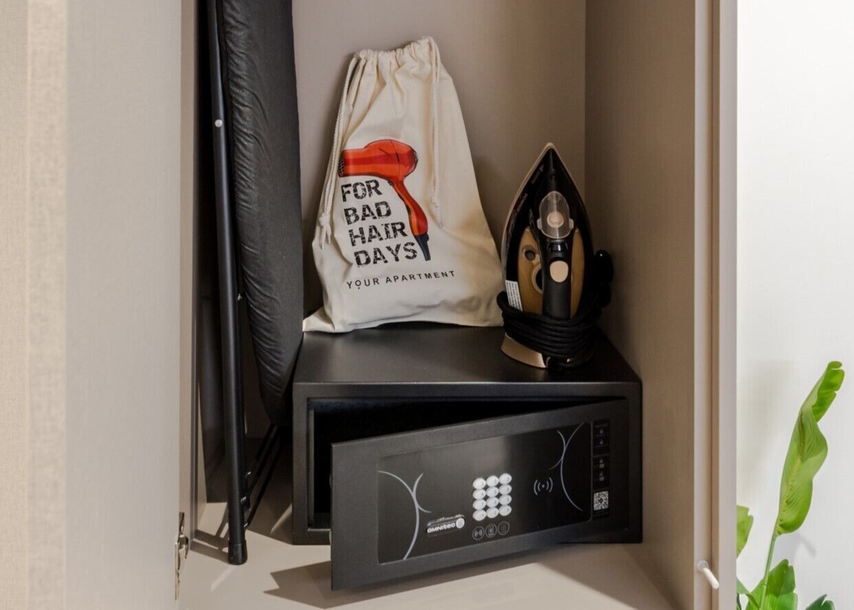 A black TV stand with a white bag labeled "For Bad Hair Days" and an iron on top.