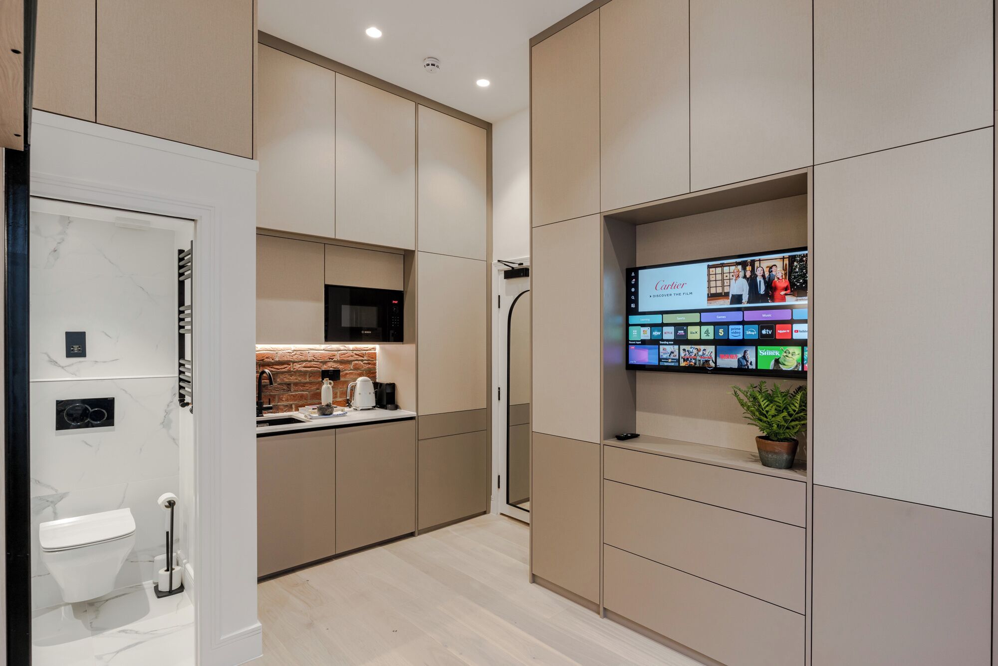 A modern kitchen with a built-in TV displaying a film, a coffee machine, and a microwave.