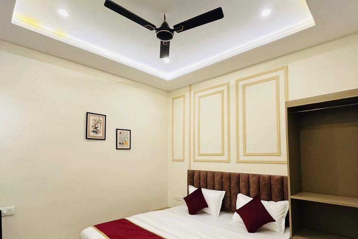 A hotel room with a bed, a ceiling fan, recessed lighting, and a built-in shelf.