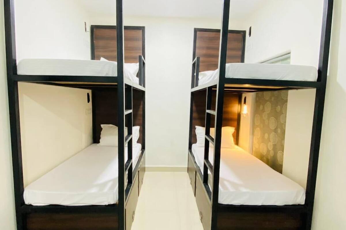 A room with two bunk beds, each with a wooden frame and white bedding.