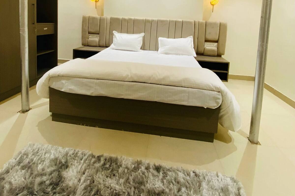 A modern bedroom with a large bed, two bedside tables, a ceiling fan, and wall-mounted lights.