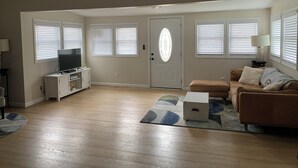 A living room with a TV, sofa, and a ceiling fan.