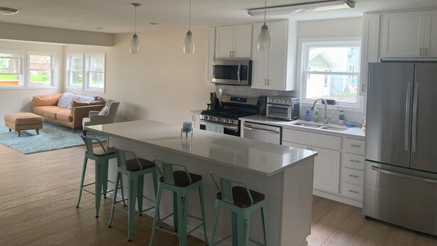 A modern kitchen with white cabinets, stainless steel appliances, and a central island with bar stools.