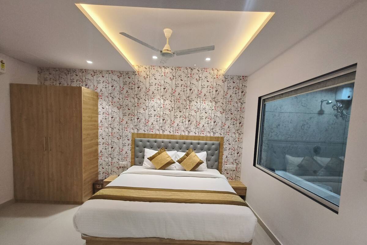 A bedroom with a bed, a wardrobe, a ceiling fan, and a window.