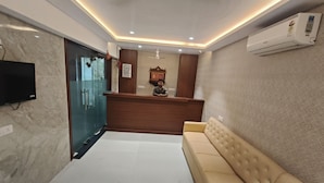 A reception area with a reception desk, a sofa, a television, and an air conditioning unit. - Hotel Morya Residency Parel (Mumbai)