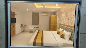 A hotel room with a bed, a desk, two chairs, a wardrobe, and a television. - Hotel Morya Residency Parel (Mumbai)