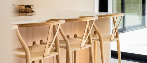 A modern kitchen with wooden bar stools and a woven basket on the counter.