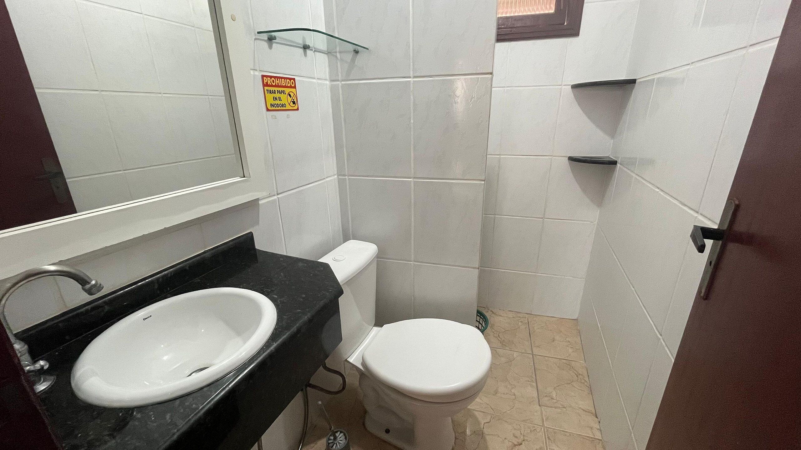 Une salle de bain avec un lavabo, des toilettes et un miroir, le tout de couleur blanche.