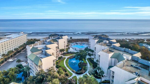 Un resort con piscina central, varias edificaciones y vista al océano.