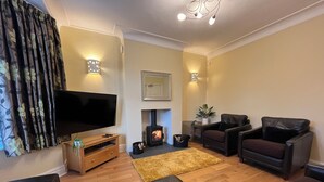 A living room with a flat-screen TV, leather sofas, a fireplace, and a wooden floor. - 1 Lathom Avenue (Morecambe)