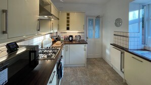 A modern kitchen with a gas stove, a coffee maker, and a toaster. There is a window with a view of the outside. - 1 Lathom Avenue (Morecambe)