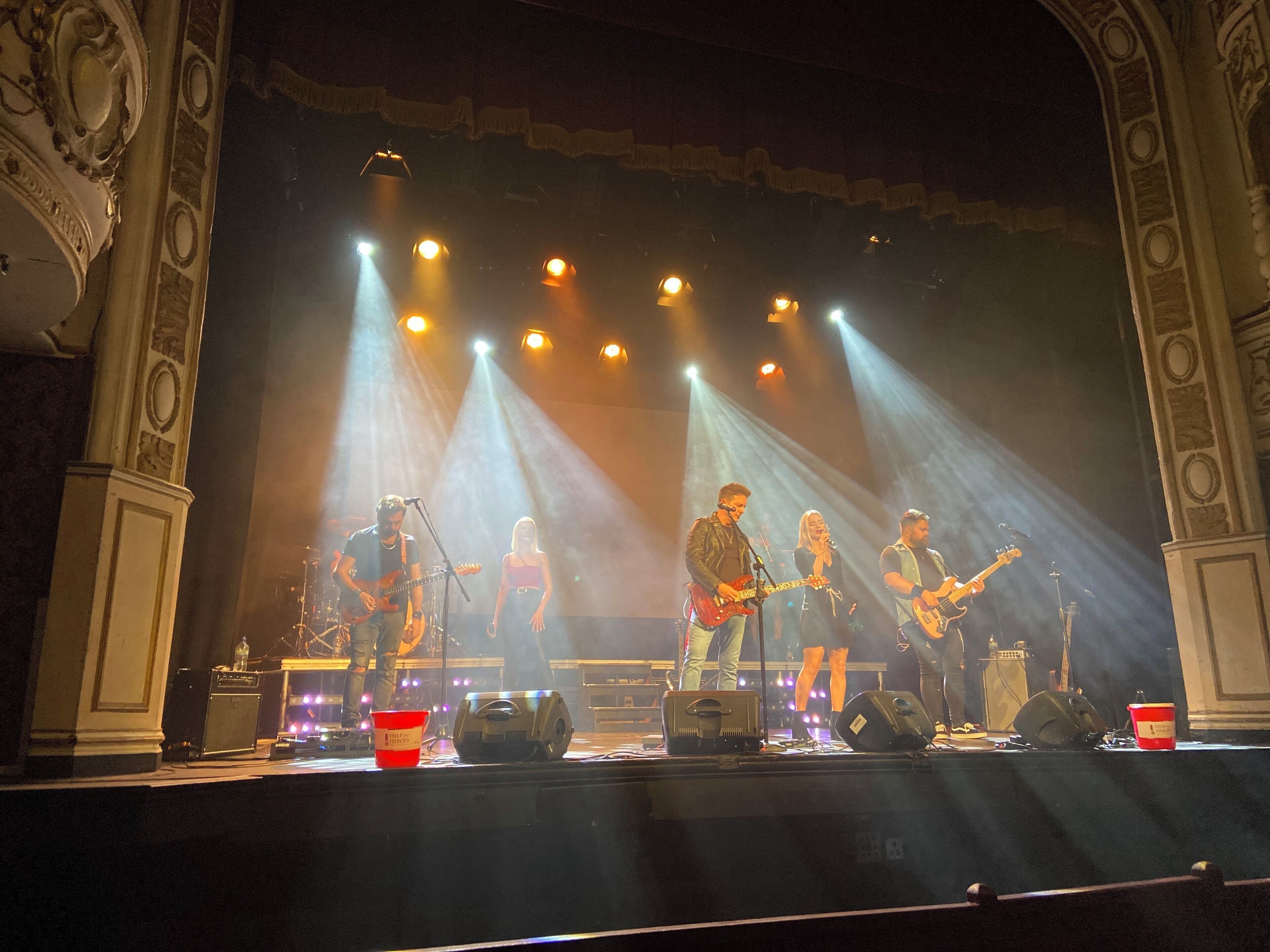 A stage with band members performing, surrounded by ornate architectural details.