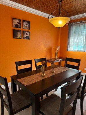 Enjoy meals in this stylish dining area with a dark table and matching chairs, surrounded by framed artworks and natural light.