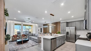 A modern kitchen with a central island, stainless steel appliances, and a dining area with a sofa and coffee table. - Potter | Avatar | Mario Kart | Near Disney 2307 (Kissimmee)