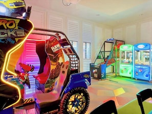 A children's play area with a large, colorful ride-on vehicle and claw machines. - Hogwarts! Avatar! Pool! Resort 7 mi 2 Disney-2307 (Kissimmee)
