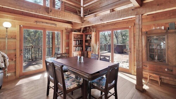 Interior de una cabaña de madera con una mesa de comedor, sillas y una estantería.