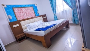 A bedroom with a bed, nightstand, and a window with curtains. - HOTEL GUIKO PALACE (Yaoundé)