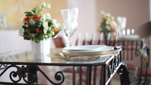 A dining table set with white plates, silverware, and a vase with flowers. - HOTEL GUIKO PALACE (Yaoundé)