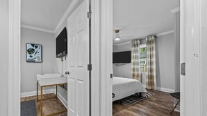 Una camera da letto con un letto, una scrivania, una TV e una finestra con tende.