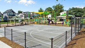 Un patio de juegos con diversas estructuras, una cancha de baloncesto y una valla.