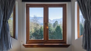 A room with a large window featuring a view of mountains and trees. - Mizpah Bed & Breakfast (Roybridge)
