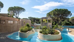 Una piscina con design circolare, circondata da fioriere con vegetazione e un muro in pietra sullo sfondo.