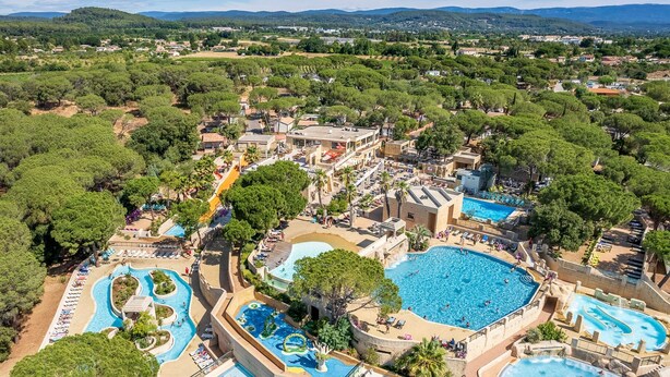 Vista aerea di un resort con diverse piscine, una grande piscina centrale e ville circostanti.