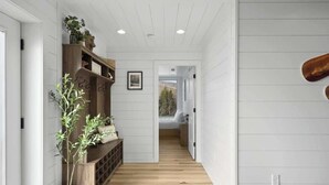 A hallway with wooden flooring, white walls, and a built-in bench with plants.