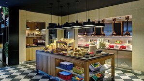 Una cucina moderna con pavimento a scacchi, mobili in legno e un'isola centrale con diversi cibi e contenitori.