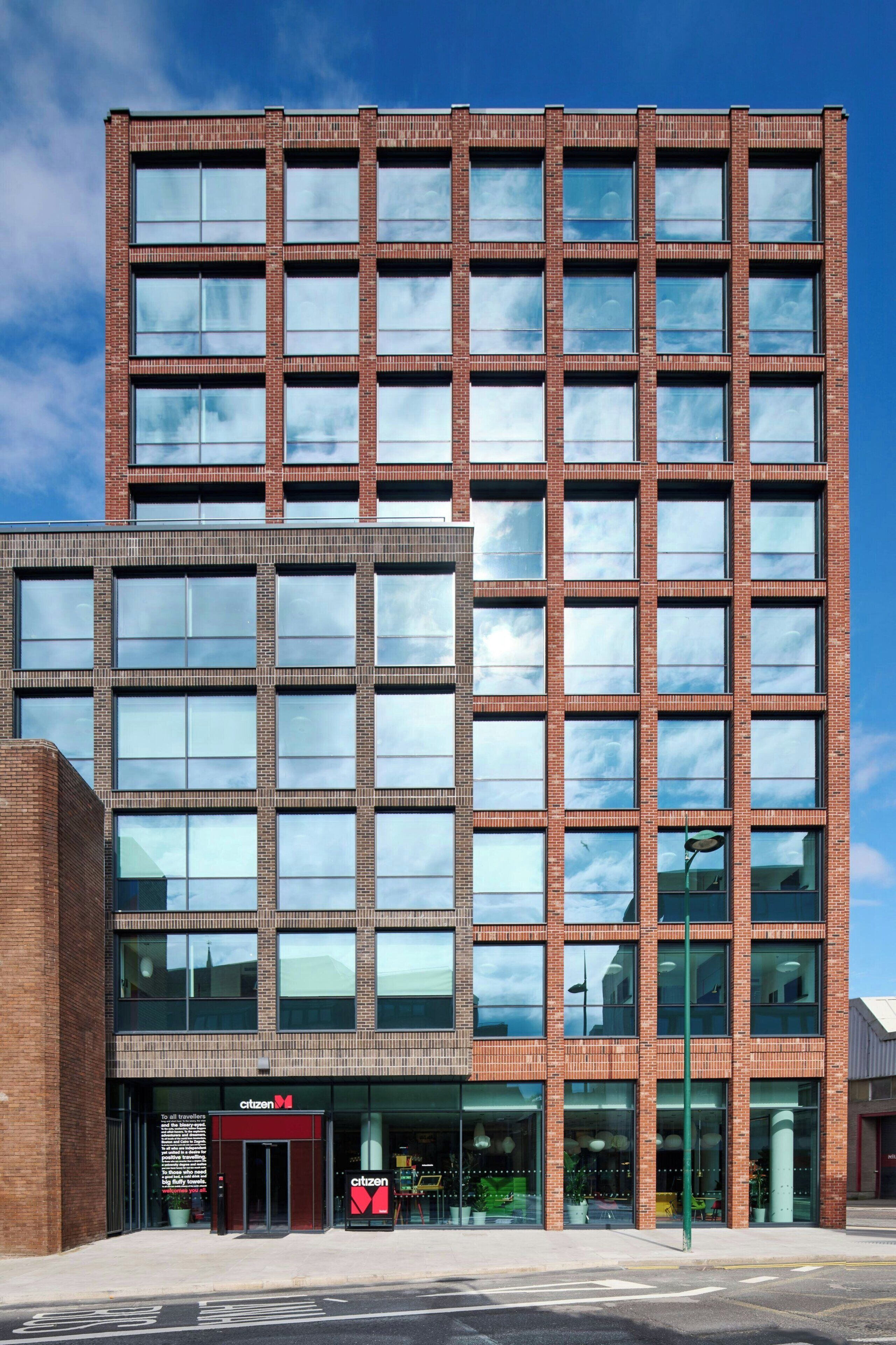 A modern building with a grid of windows and a prominent entrance with a sign.