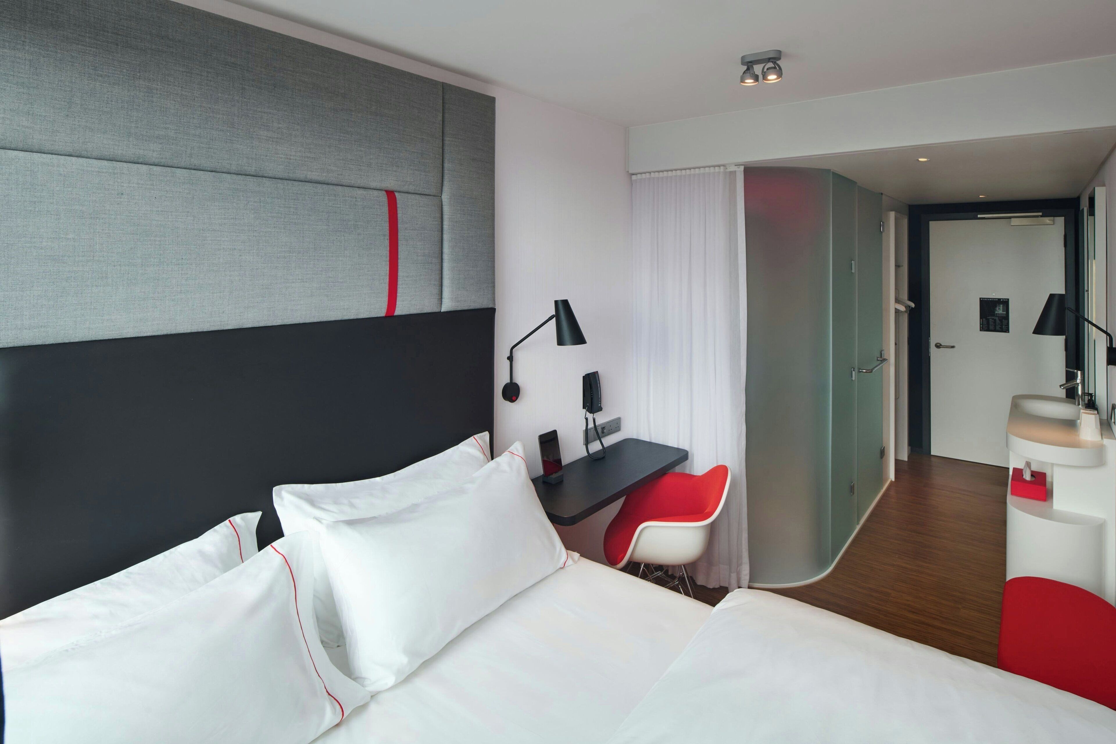 A hotel room with a bed, a desk, a chair, and a bathroom.
