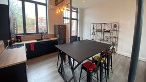 Une cuisine moderne dotée d’un grand îlot central, d’une table à manger avec des chaises et d’une étagère décorative en métal.