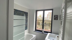 Une salle de bain moderne avec une baignoire, un lavabo et une fenêtre.