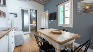 A modern kitchen with a wooden table, black chairs, and a large window with green shutters. - Central Nest by MMega (Florence)