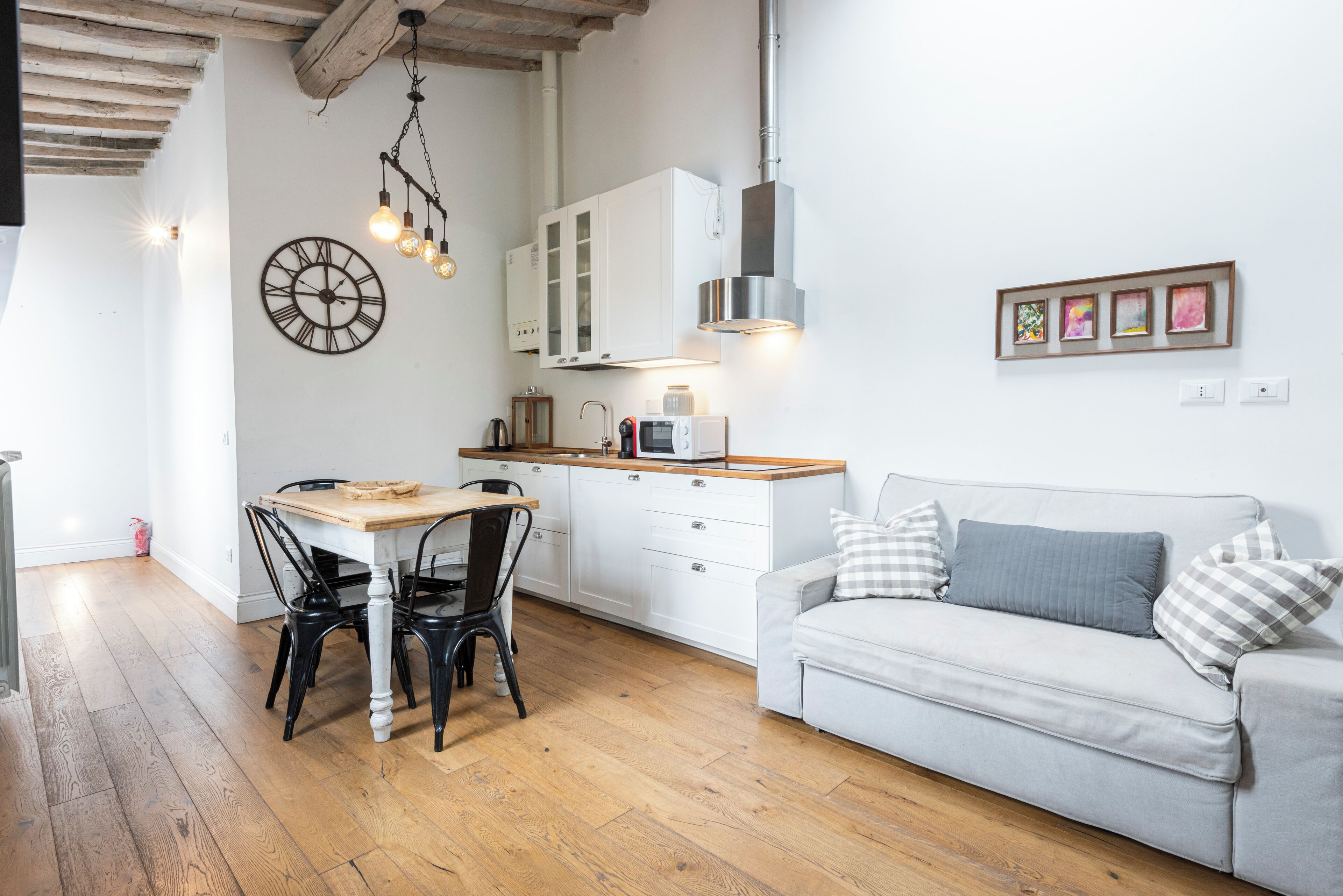 Una cucina moderna con mobili bianchi, un tavolo da pranzo in legno e sedie nere.