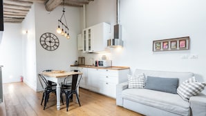 A modern kitchen with white cabinets, a wooden dining table, and black chairs. - Central Nest by MMega (Florence)