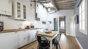 A modern kitchen with white cabinets, a wooden countertop, and black chairs around a wooden table. - Central Nest by MMega (Florence)