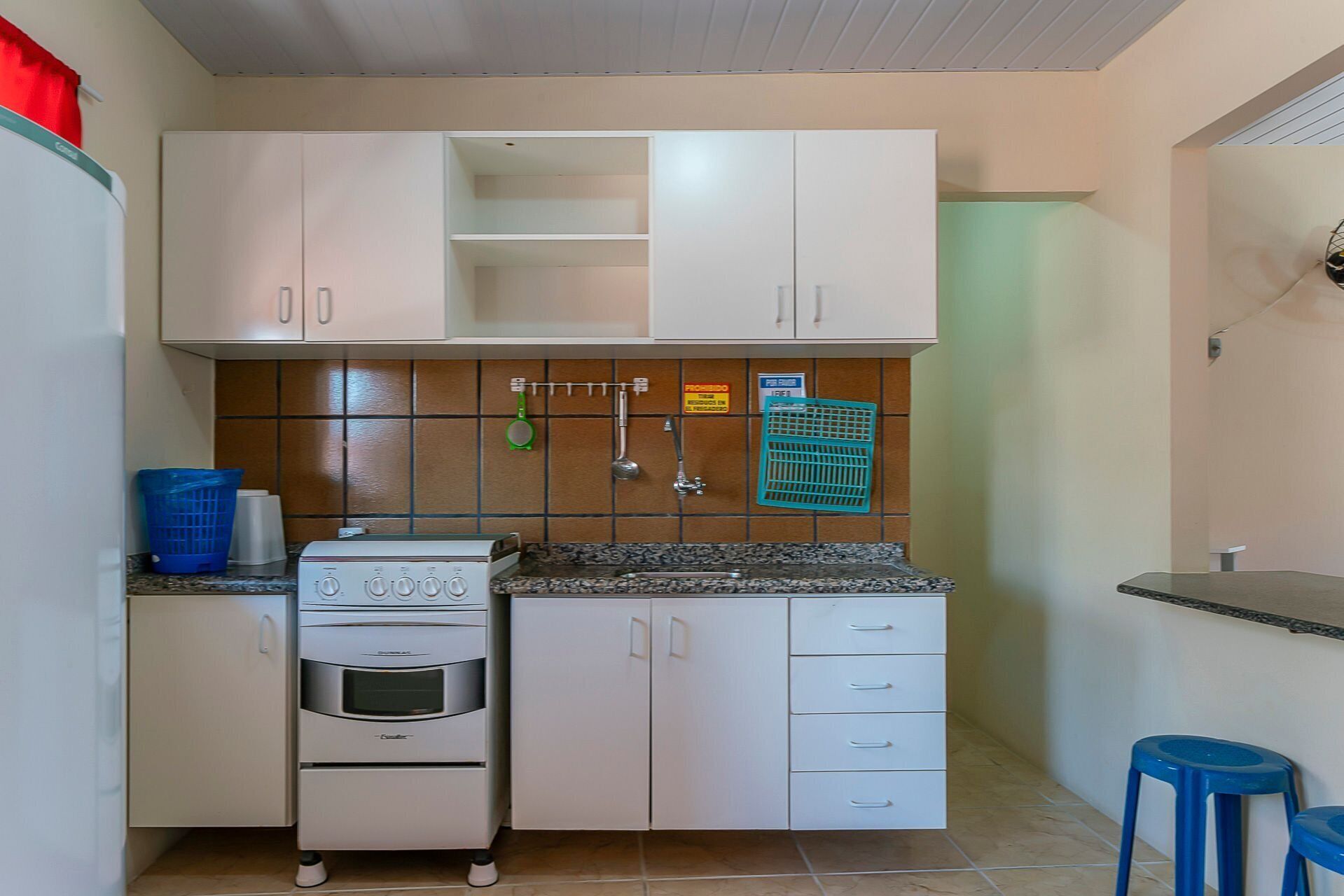 A compact kitchen with white cabinets, a built-in oven, and a tiled backsplash.