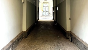 Pitkä, kapea käytävä, jossa on laatoitettu lattia ja valkoiset seinät.