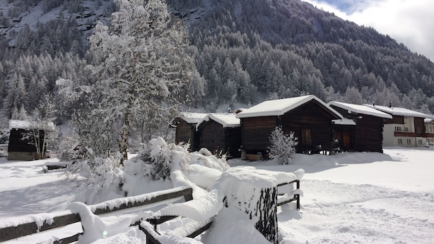 Eine schneebedeckte Lodge mit Holzhütten und Bergblick.
