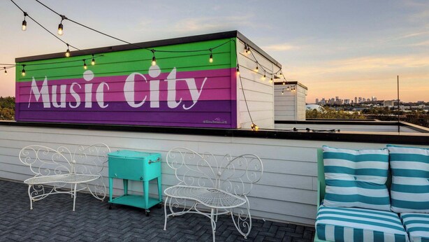 Une terrasse sur le toit avec une enseigne « Music City », des sièges en plein air et une vue panoramique sur la ville.