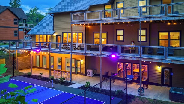 A multi-story hotel with outdoor seating and a tennis court.