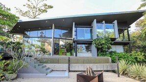A modern house with a concrete staircase leading to a glass door, surrounded by greenery. - Casa Ceibo - Private Villa with Pool (Puntarenas Province)