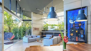 A modern interior with a wooden dining table, blue sofas, and a large painting of a night scene. - Casa Ceibo - Private Villa with Pool (Puntarenas Province)