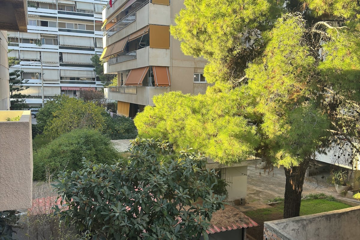 A residential area with multi-story buildings, a large tree, and a small garden area.